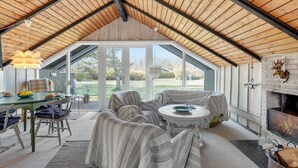 Una habitación acogedora de techos altos con chimenea, asientos cómodos y vistas al exterior.