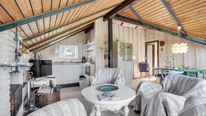 Un interior acogedor con techo de madera, una zona de cocina y un espacio de estar con una mesa redonda.