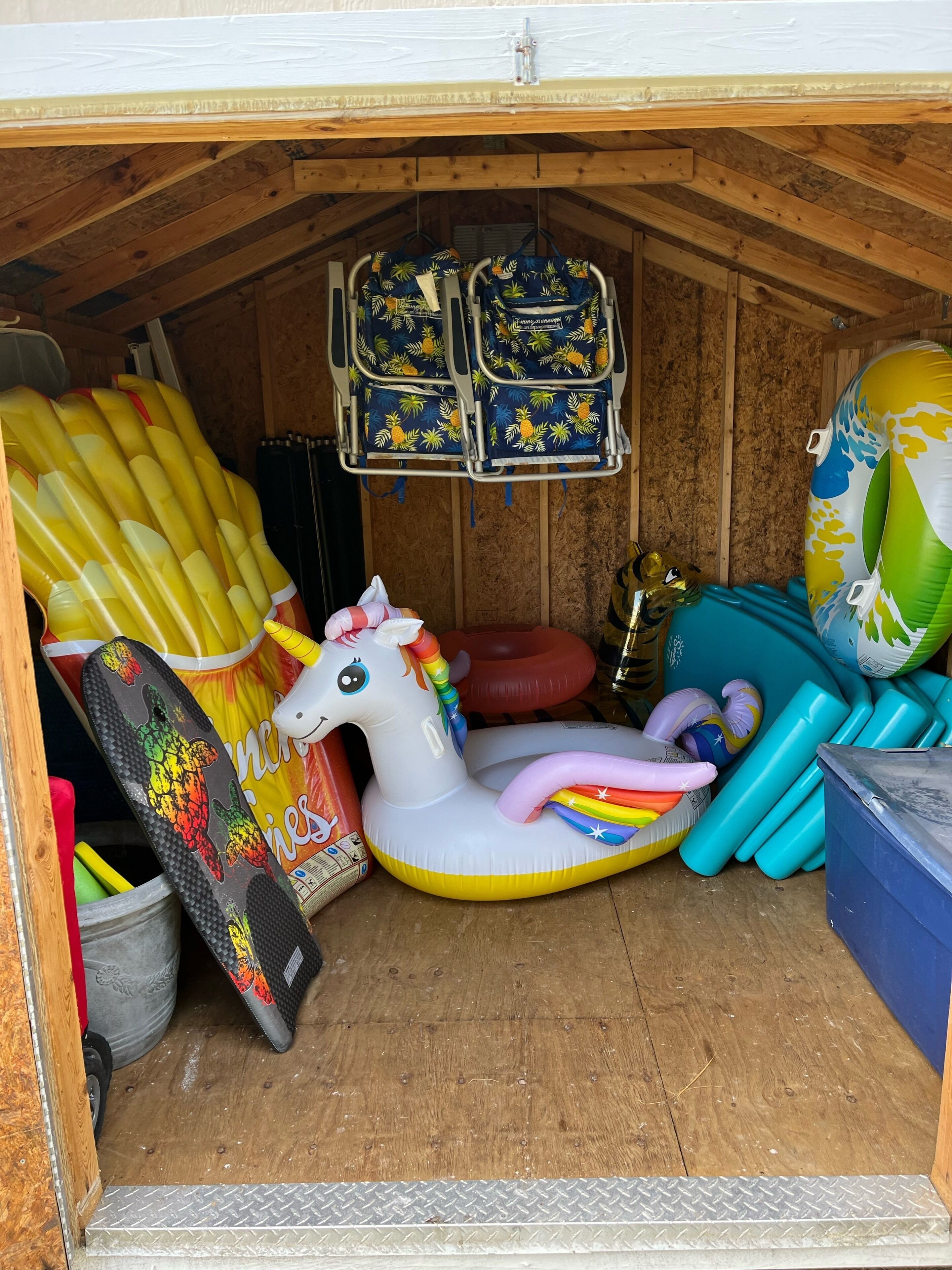 A storage area with various inflatable items, including a unicorn float and multiple beach balls.