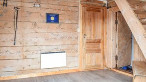 L’intérieur d’une cabane en bois, avec un certificat accroché au mur, une porte et une fenêtre.