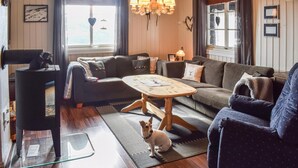 Uma sala de estar aconchegante com um sofá, uma mesa de centro e um cãozinho.