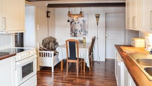 Uma cozinha com armários brancos, uma mesa de jantar de madeira e um cão sentado sobre a mesa.
