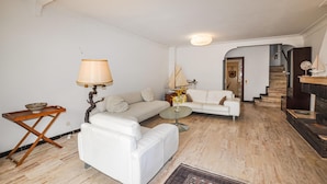 Un salon moderne avec un canapé blanc, une petite table, une lampe et un escalier menant à un autre niveau.