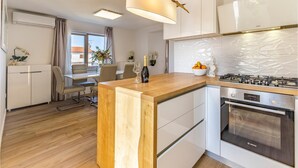 Eine moderne Küche mit einer Holzinsel, Edelstahlgeräten und einem Essbereich mit Tisch und Stühlen.