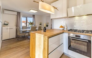 A modern kitchen with a wooden island, stainless steel appliances, and a dining area with a table and chairs.