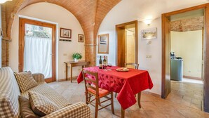 A dining area with a table set for two, a sofa, and a kitchen visible through an open door. - 6 bedroom nice home in Montaione (Montaione)
