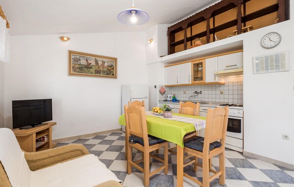 Un espace de vie compact comprenant un coin repas, une kitchenette et un téléviseur.