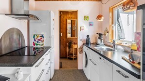 A compact kitchen with a modern stove, a washing machine, and a sink. - 3 bedroom lovely home in Gedser (Gedser)
