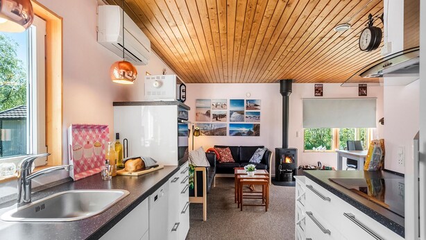 A modern kitchen with a wood ceiling, a built-in stove, and a dining area with a sofa and coffee table. - 3 bedroom lovely home in Gedser (Gedser)