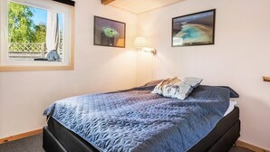 A bedroom with a bed, a window with a view of greenery, and two framed pictures on the wall. - 3 bedroom lovely home in Gedser (Gedser)