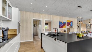Una cucina moderna con un'isola grande, pareti rivestite in legno e vista su una sala da pranzo.