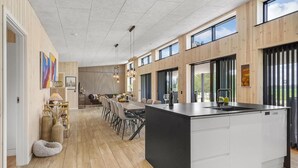 Una cucina moderna con una grande isola, rivestimenti in legno e ampie finestre.