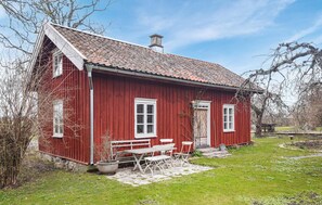 A red wooden house with a tiled roof, a front door, and a small porch with benches. - Amazing home in Lidköping with kitchen (Lidköping)