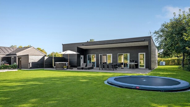 Una casa moderna con patio, posti a sedere all'aperto e un trampolino.