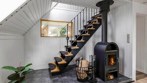 Un intérieur moderne avec un escalier en colimaçon noir, un poêle à bois et une plante en pot.