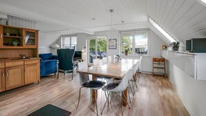 Une cuisine spacieuse avec un coin repas, des meubles en bois et une grande fenêtre qui laisse entrer la lumière naturelle.