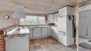 Kompakti keittiö, jossa on mikroaaltouuni, jääkaappi ja puiset kaapit.