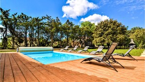 Ein Schwimmbecken mit Holzterrasse und Liegestühlen.