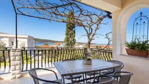 A balcony with a table and chairs, overlooking a coastal town.