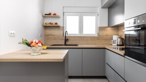 A modern kitchen with grey cabinets, a wooden countertop, a sink, and a built-in oven.