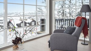 A modern living room with a large window, a grey armchair, a floor lamp, and a decorative branch with ornaments. - Beautiful home in Rauland with sauna (Rauland)