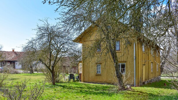 Una casa de madera con techo inclinado, rodeada de césped y árboles.