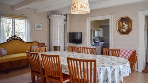 Un comedor con una mesa redonda, sillas de madera, un sofá, un televisor y una cocina al fondo.