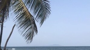 A beach with clear skies, calm water, and palm trees. - Breathtaking Oceanview Villa in Paradise (HUMACAO)