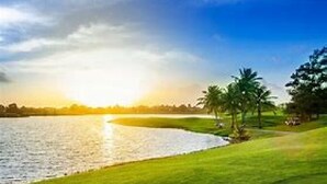 A golf course with a water body, trees, and a clear sky. - Breathtaking Oceanview Villa in Paradise (HUMACAO)