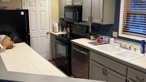 A kitchen with a refrigerator, stove, microwave, and sink.