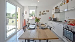 Una cocina moderna con una mesa de comedor de madera, armarios blancos y electrodomésticos de acero inoxidable.