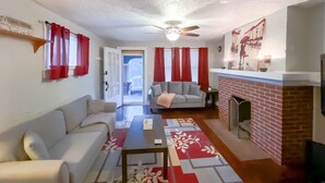 Un salon avec un canapé, une table basse et une cheminée. Une porte donne accès à un balcon.