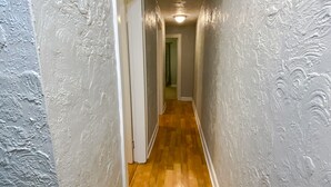 Un couloir étroit doté d’un plancher en bois et de murs à texture.