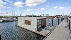 Ein moderner Yachthafen mit einem kleinen, zeitgemäßen Gebäude, das einen Glasvordereingang und eine Wendeltreppe aufweist.