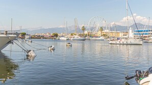 A marina with boats docked, a Ferris wheel, and buildings in the background. - Awesome apartment in Viareggio with WiFi (Viareggio)