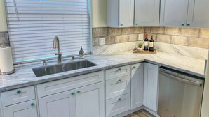 A modern kitchen with a sink, faucet, and countertop. There are cabinets, a dish rack, and a potted plant on the counter. - ★★★★ Brand New Beautiful Ocean View Home ★★★★ (Whitethorn)