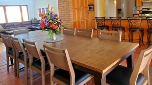 A spacious dining area with a wooden table and chairs, a brick wall, and a kitchen in the background. - Close to downtown but feels like country-Very Private! Refreshing pool & hot tub (Tucson)