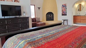 A bedroom with a large bed, a TV, a fireplace, and a kitchen area. - Close to downtown but feels like country-Very Private! Refreshing pool & hot tub (Tucson)