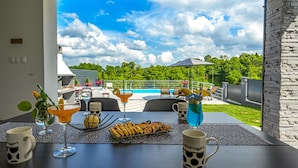 A dining area with a view of a swimming pool and outdoor seating.