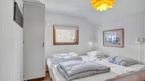 Une chambre à coucher avec un lit, une fenêtre, une lampe fixée au mur et un luminaire au plafond.