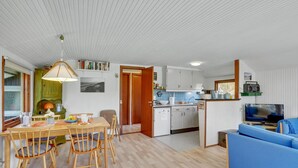 Un espace de vie compact comprenant un coin repas, une kitchenette et un coin salon avec un téléviseur.