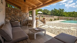 A covered outdoor seating area with a stone wall, a pool, and a view of the surrounding landscape. - Beautiful home in Jadranovo (Jadranovo)