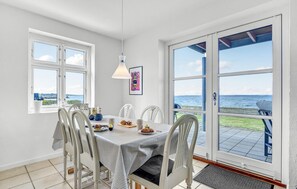 Enjoy meals with a view of the sea from this dining area, featuring a table for four and a large window.