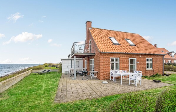 Enjoy a scenic coastal view from the spacious patio with a dining set and outdoor seating.