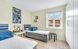 Cozy retreat with two single beds, a bedside table, and a large window offering a view of the outside.