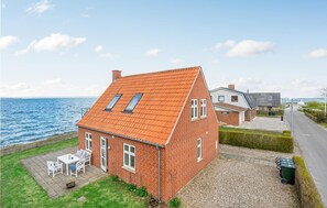 Charming brick house with a sloped roof, adjacent to a road and overlooking the sea.