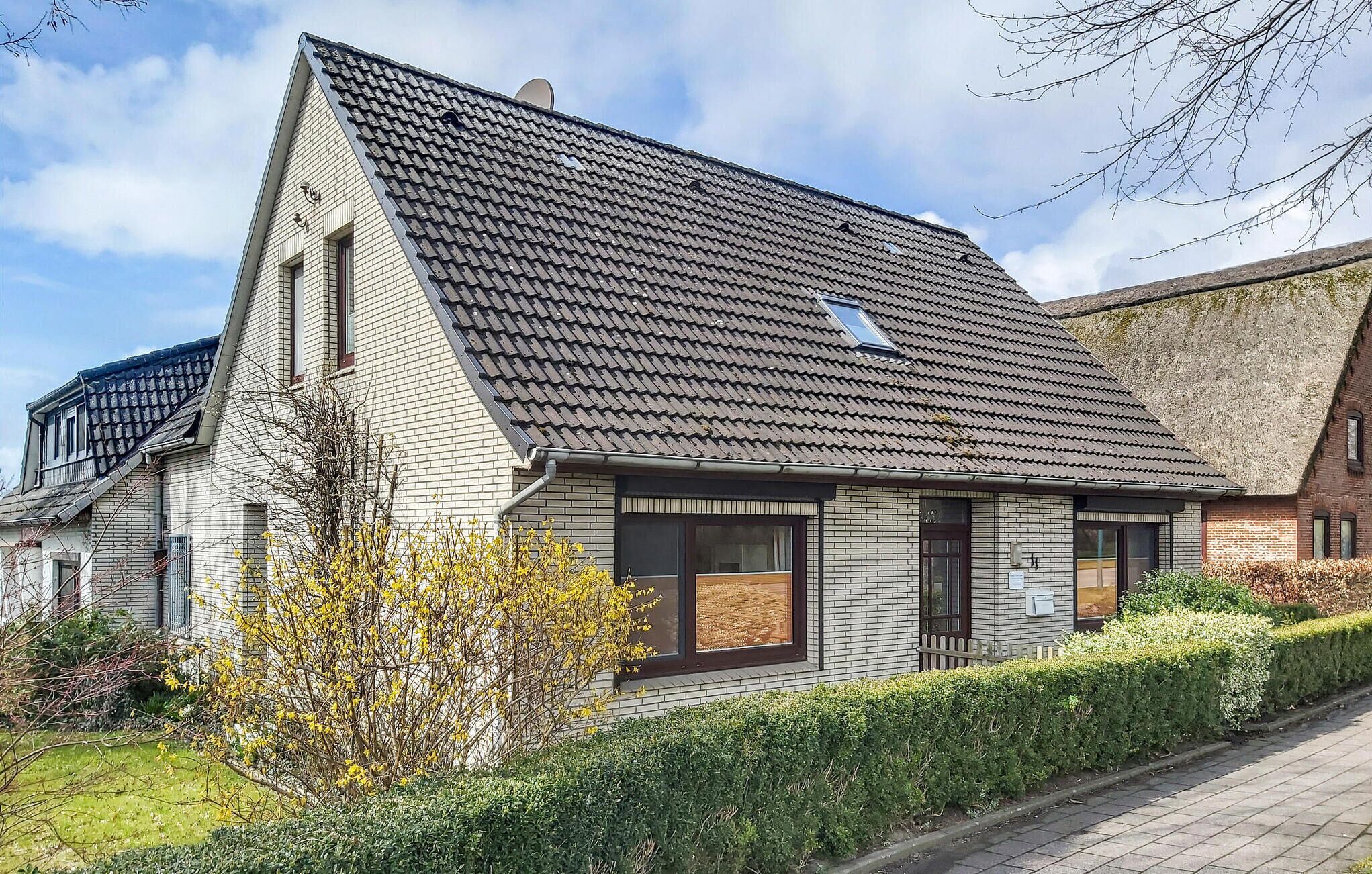 Ein modernes, zweistöckiges Haus mit geneigtem Dach, großen Fenstern und einem gepflegten Garten.