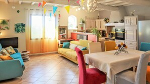 Un soggiorno accogliente con divano, poltrone, un tavolo da pranzo e una cucina sullo sfondo.