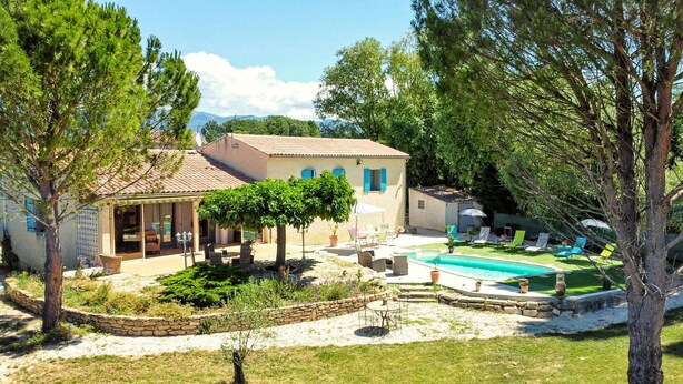 Una casa circondata da alberi e un prato curato, con piscina.