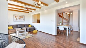 Una sala moderna con un sofá, una mesa de centro y un comedor con una mesa lista para dos personas.